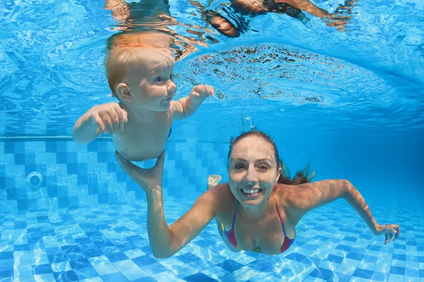 Child swimming lesson - baby with moher dive underwater in pool