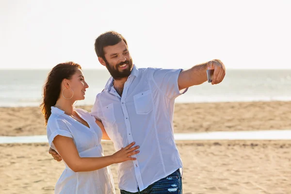Happy family on honeymoon holidays - just married loving couple have fun and taking selfie for social network on sea beach. Lifestyle and people outdoor activity on summer vacation on tropical island. — Stock Photo, Image
