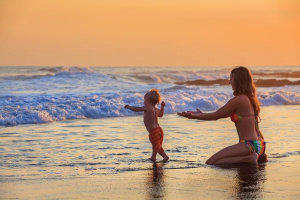 Family swimming fun in sea beach surf Happy mother, baby son first step - toddler run to ocean wave on sunset sky background Child outdoor activity, parent lifestyle, summer holiday in tropical island — Stok Foto