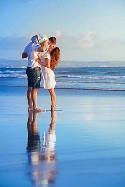 Familia feliz caminando con diversión en la playa de la mar al atardecer — Foto de Stock