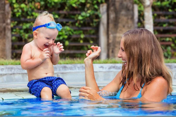 Lyckligt barn simma med vacker mor i poolen — Stockfoto