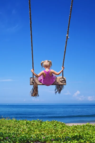 Child on flying high on rope swing on sea beach — Stock Photo, Image