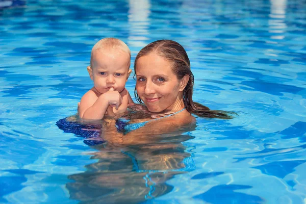 Little child swimming in pool with mother