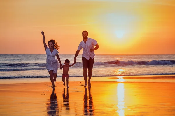 Padre, madre, bebé divertirse en la playa al atardecer — Foto de Stock