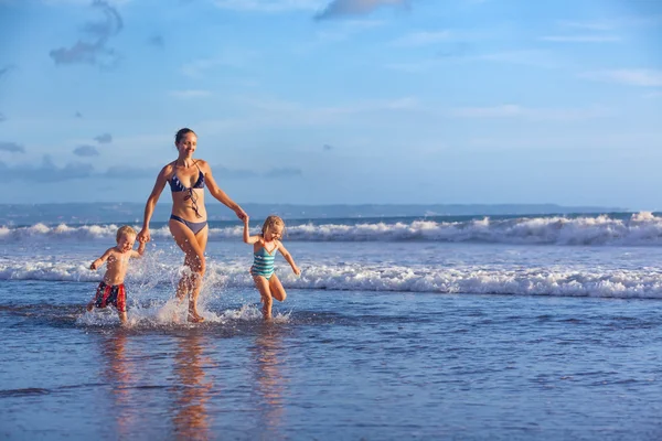 Familia feliz con diversión a lo largo de surf de la puesta de sol playa — Foto de Stock