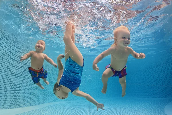 Crianças nadam e mergulhar debaixo d'água com diversão na piscina — Fotografia de Stock