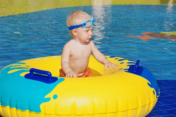 Child sunbathing, swim with inflatable toy in swimming pool — Stock Photo, Image