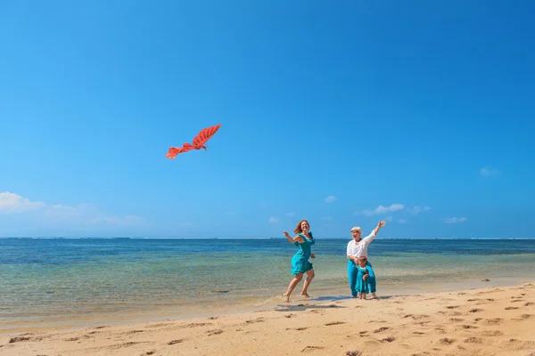 Grand-mère, mère et enfant lançant le cerf-volant sur la plage de la mer — Photo