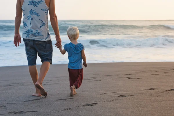 Father and son walks on sunset ocean beach — Stock Photo, Image