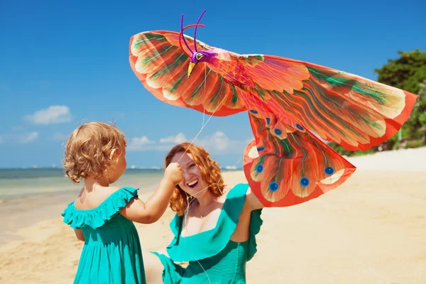 Wandelen op oceaan strand moeder en kind lancering kite — Stockfoto