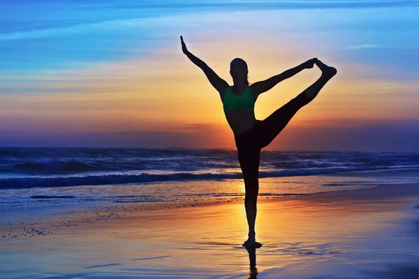 Silhueta de mulher, estendendo-se em retiro de yoga na praia do sol — Fotografia de Stock