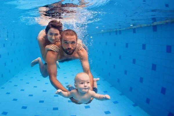 Diversão em família na piscina - mãe, o pai, o mergulho do bebê na água — Fotografia de Stock