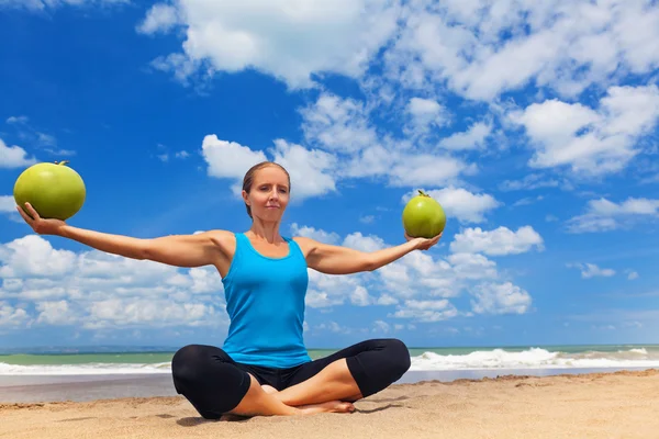 Mulher apta a se exercitar com coco jovem na praia do oceano. Mulher desportiva a fazer exercício. Fitness mulher férias de verão acampamento desportivo. Estilo de vida esportivo ativo, nutrição saudável, dieta natural para perda de peso . — Fotografia de Stock