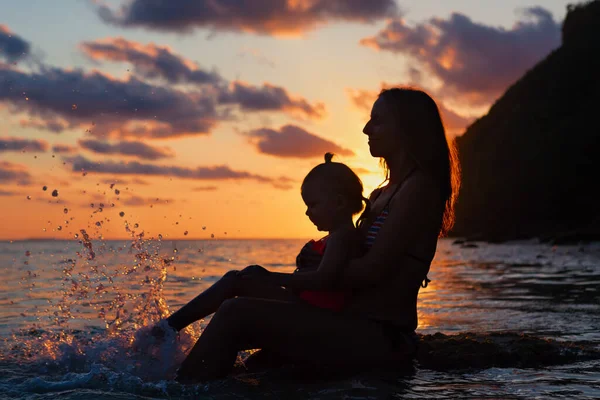 幸せな人々は夏のビーチの休日に楽しんでいます 娘と一緒に若い母親は海のプールでリラックスします 夕日の空の美しい景色を見て 健康的な家族のライフスタイル 熱帯の島での夏の旅行 — ストック写真