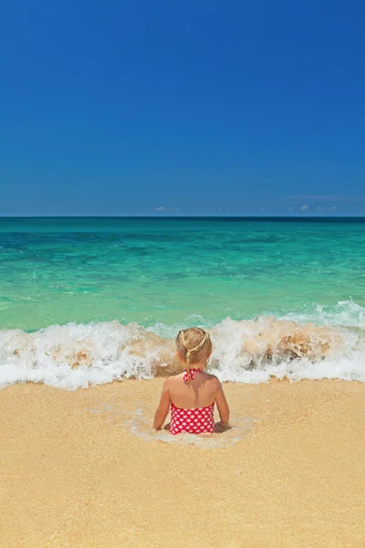 Girl sitting in the ocean breaking waves on the sand beach — Stock Photo, Image