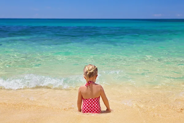 Meisje, zittend op het zand strand — Stockfoto