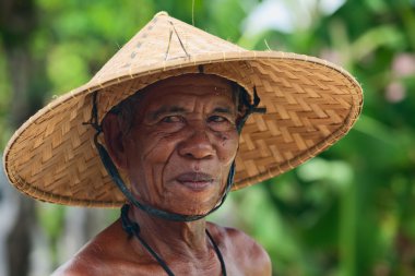 Kimliği belirsiz bir eski Balinese çiftçi ile geleneksel hasır şapka çapında ekledi kırışmış yüzüne portresi