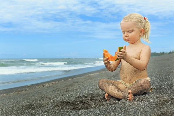 Menina bonita na praia mar comer papaia madura — Fotografia de Stock