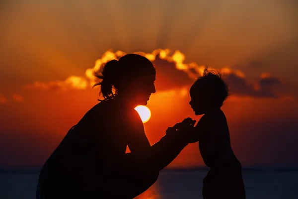 Gelukkig moeder en vreugdevolle zoon zonsondergang silhouet — Stockfoto