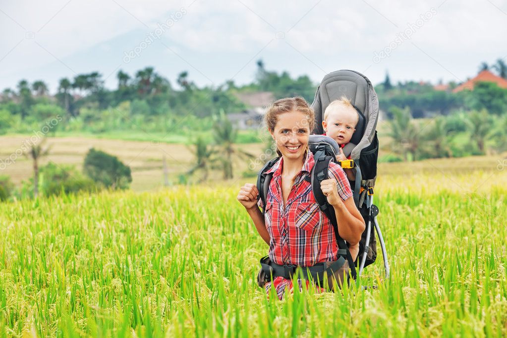 Mother with baby in carrying backpack walking on rice terraces