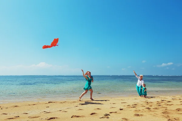 Famille heureuse avec une aile rouge sur la plage de la mer — Photo