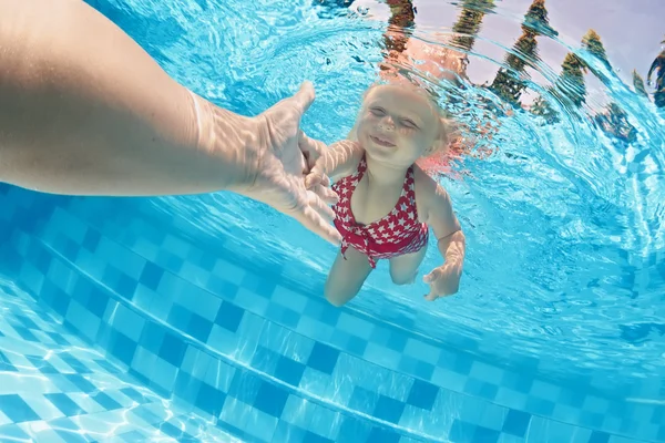 Kind onderwater zwemmen in het zwembad met ouders — Stockfoto