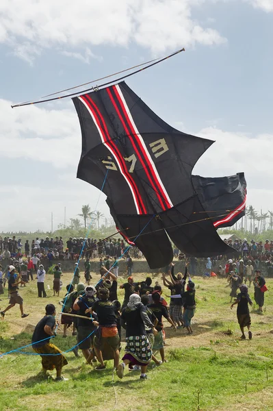 Balinese men try to catch big traditional kite — Stock fotografie