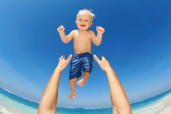 Father throwing up high in the air a happy child — 图库照片