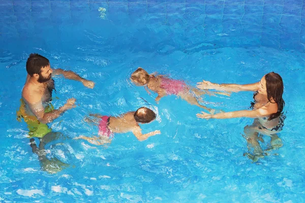 Kinderen met ouders onderwater zwemmen in blauwe zwembad — Stockfoto