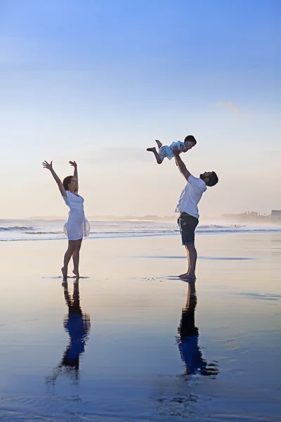 Família positiva se divertindo na praia do mar de areia preta — Fotografia de Stock