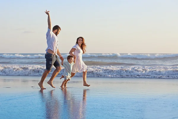 Pozytywny rodziny biegnącej wzdłuż brzegu morza na plaży — Zdjęcie stockowe