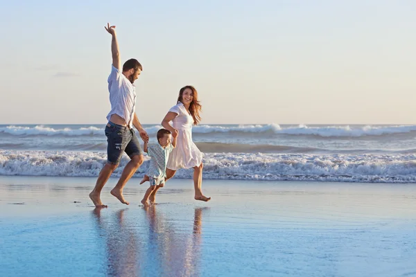 Familiar positiva corre a lo largo del borde del mar en la playa — Foto de Stock