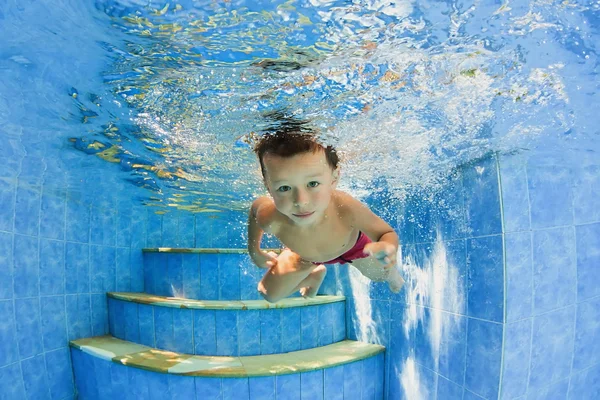 Criança sorridente natação subaquática na piscina — Fotografia de Stock