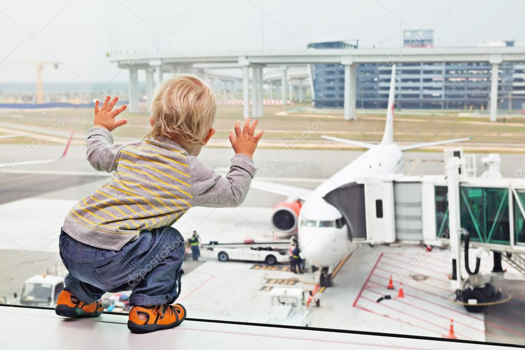 Baby boy in airport transit hall looking at airplane