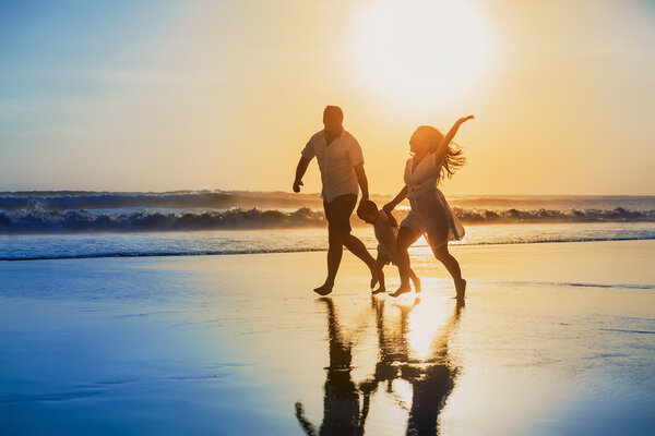 Позитивные семья работает с весело на пляж заката.