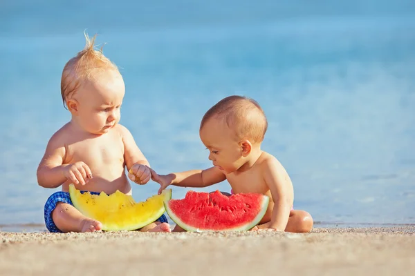 Children after swimming have fun and eat fruits on beach — Stock Image Children after swimming have fun and eat fruits on beach Royalty Free Stock Images