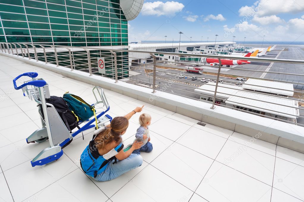 Young mother show to baby boy airplanes in airport