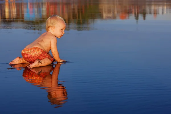 Klein kind heeft een leuke op zwarte zand zonsondergang zee strand — Stockfoto