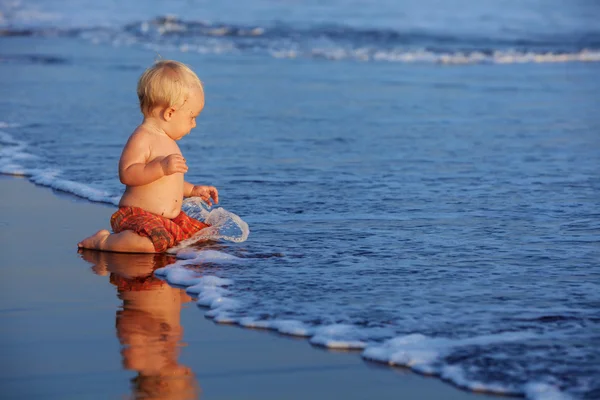 Criança pequena tem uma diversão na praia do mar do sol areia preta — Fotografia de Stock