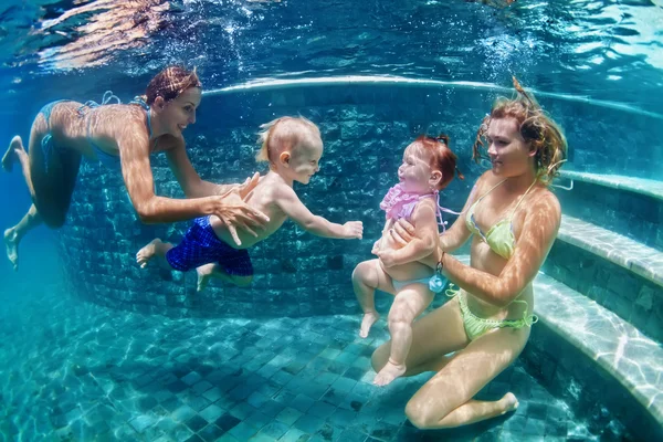 Moeders met kinderen zwemmen onder water in blauwe strand zwembad — Stockfoto