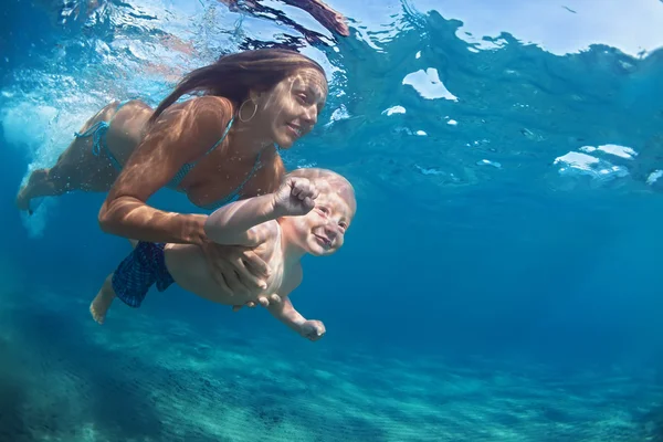 Mother with child swim underwater in blue beach pool