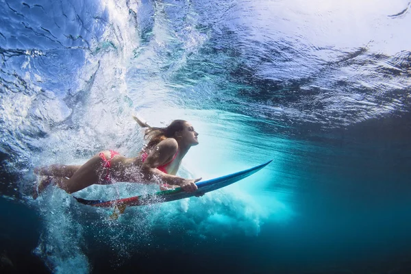 Foto submarina de muchacha con el tablero de bucear bajo la onda de océano — Foto de Stock