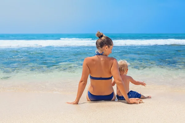 Madre con bambino che si siede sulla spiaggia di sabbia bianca — Foto Stock