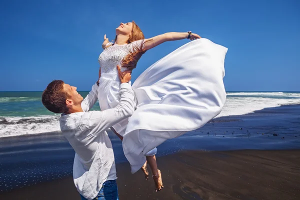 Young loving couple have a fun on sea black sand beach — Stok Foto