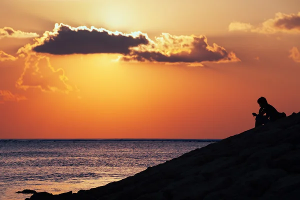 Zwarte silhouet van denken man zit alleen op zee strand — Stockfoto