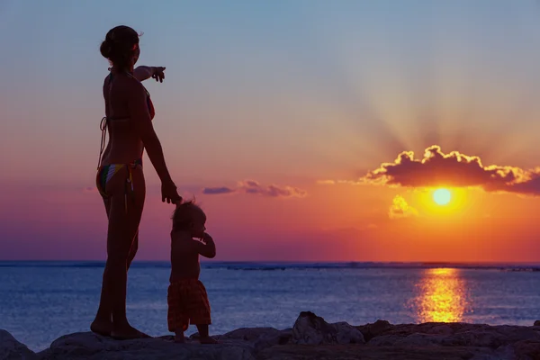 Moeder met zoon kijken naar zonsondergang zon op het strand — Stockfoto