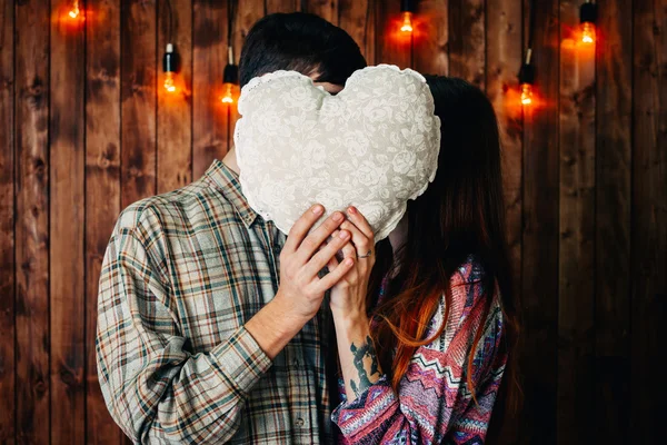 Um casal a segurar um coração. Hipsters em fundo de madeira vintage . — Fotografia de Stock