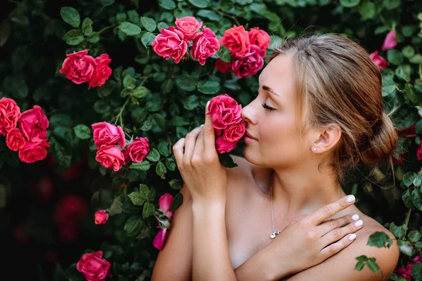 バラ園のロマンチックな若い女性の屋外写真 黒いドレスを着た赤い唇の女の子 バラの茂みを背景にした若いモデル スタイリッシュな女性 — ストック写真