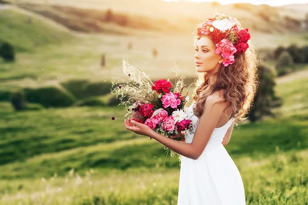 Moda beleza modelo menina com flores no cabelo em um vestido de noiva . — Fotografia de Stock