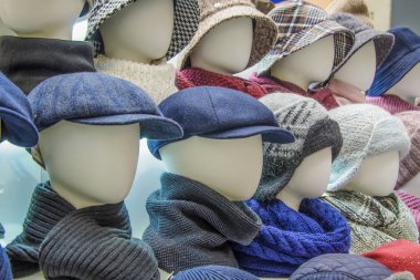 Showcase of shop with variety of men's and women's headdresses for autumn and winter seasons - caps, knitted hats, scarves. Demonstration of goods, seasonal sales. clipart
